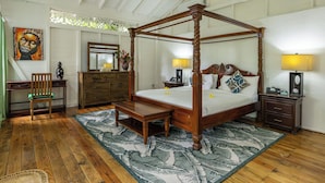 Una cama con dosel de madera, una mesita de noche con lámpara, una silla, un aparador y un cuadro en la pared.