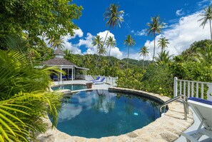 A swimming pool surrounded by palm trees and a gazebo. - Fond Doux Eco Resort (Soufrière)