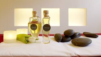 Uma mesa com dois frascos de perfume, uma vela e pedras.