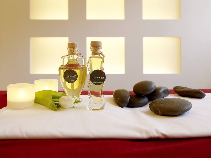 Uma mesa com dois frascos de perfume, uma vela e pedras.