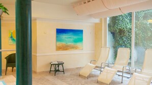 Un espace détente avec des fauteuils inclinables, un tableau et une petite table.