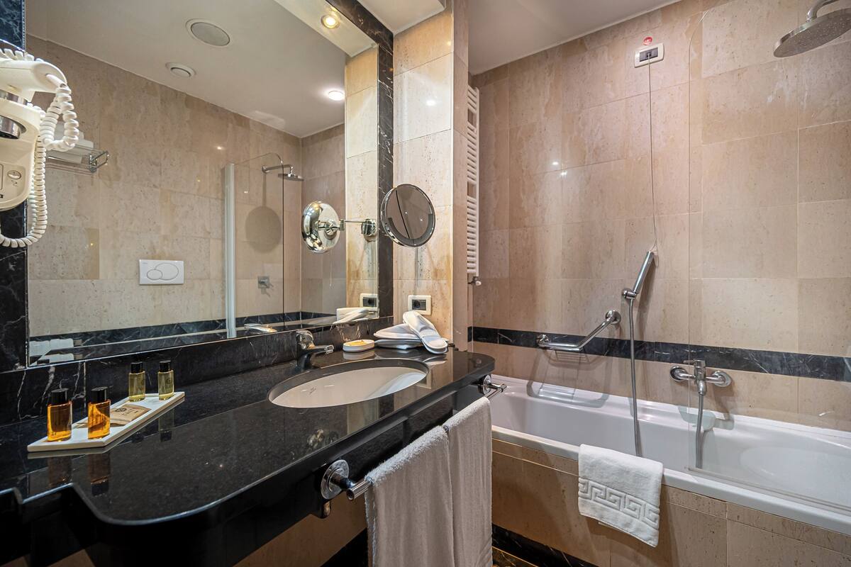 Ein modernes Badezimmer mit Waschbecken, Badewanne, Dusche und Schminktisch mit Spiegel.