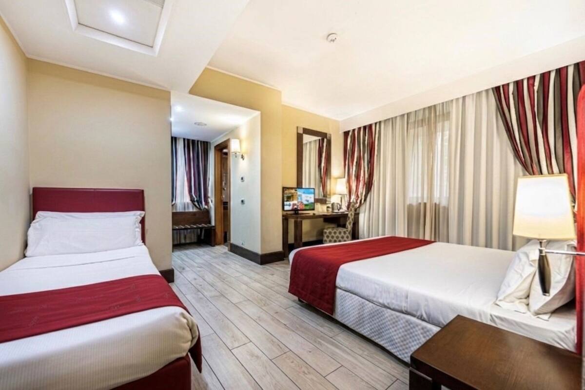 Ein Hotelzimmer mit zwei Betten, einem Schreibtisch, einem Sessel, einem Fernseher und einem Badezimmer.