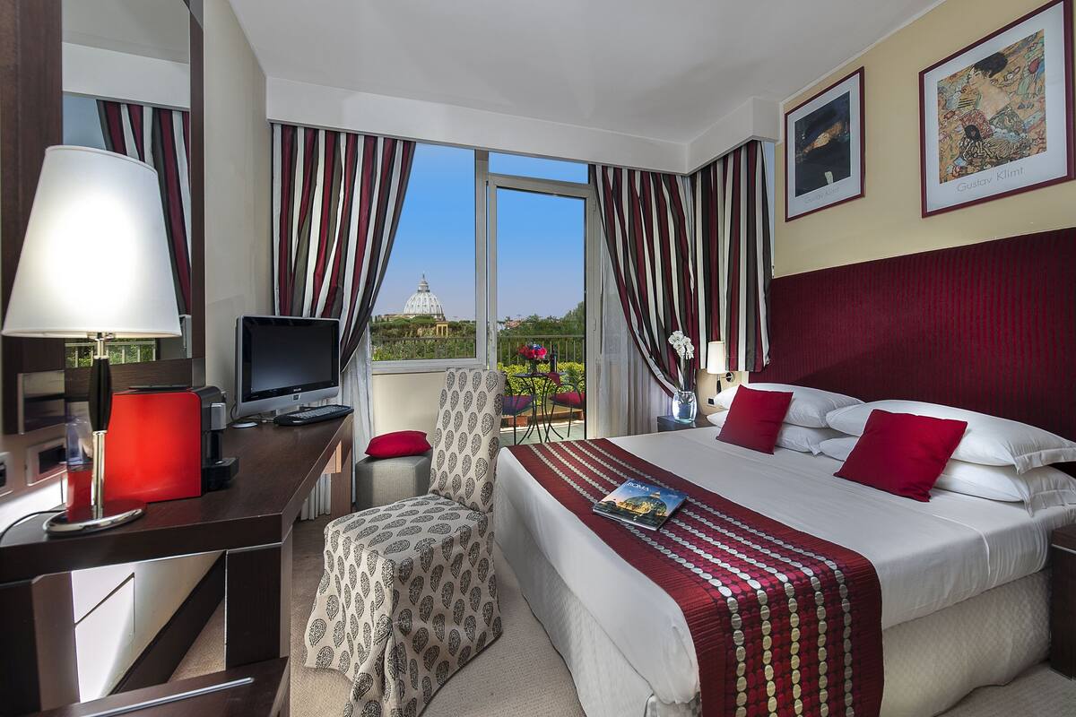 Ein Hotelzimmer mit Bett, Schreibtisch, Stuhl und Blick auf eine Kuppel durch das Fenster.