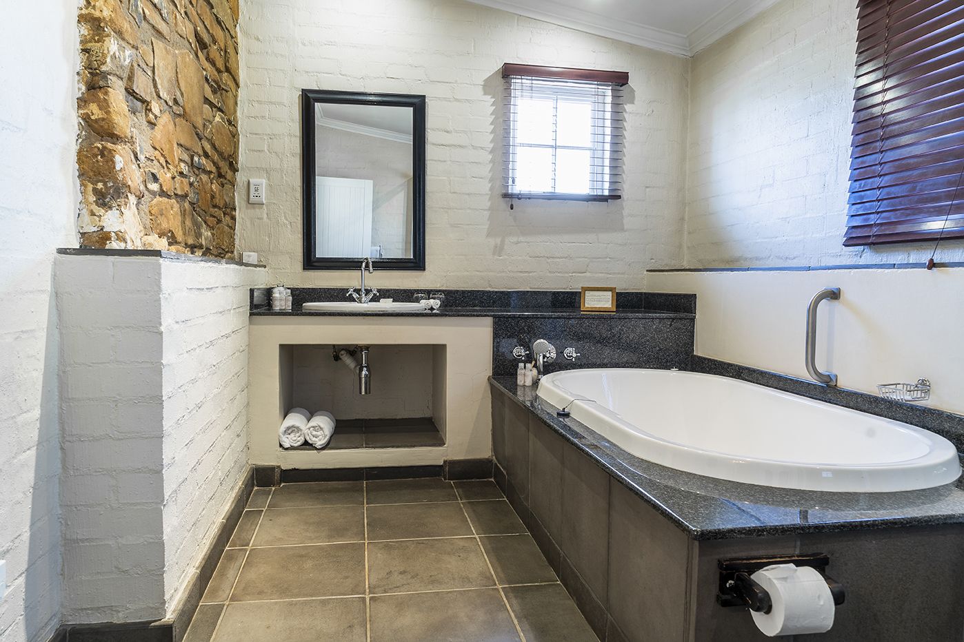 Un bagno con vasca, lavabo, specchio e finestra.