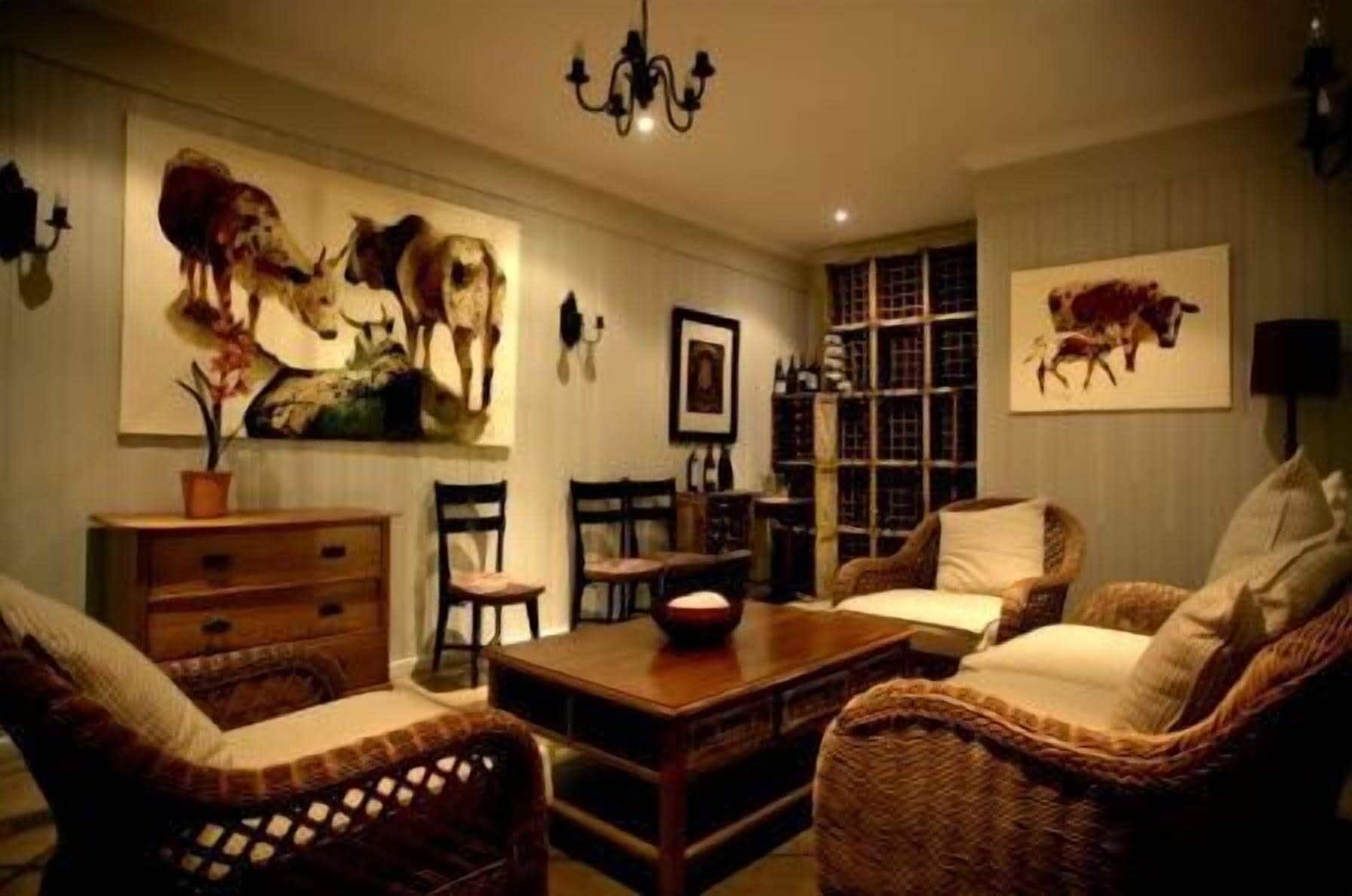 Una sala de estar acogedora con muebles de mimbre, una mesa de centro de madera y cuadros de animales colgados en la pared.