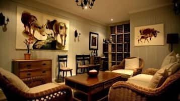 Una sala de estar acogedora con muebles de mimbre, una mesa de centro de madera y cuadros de animales colgados en la pared.