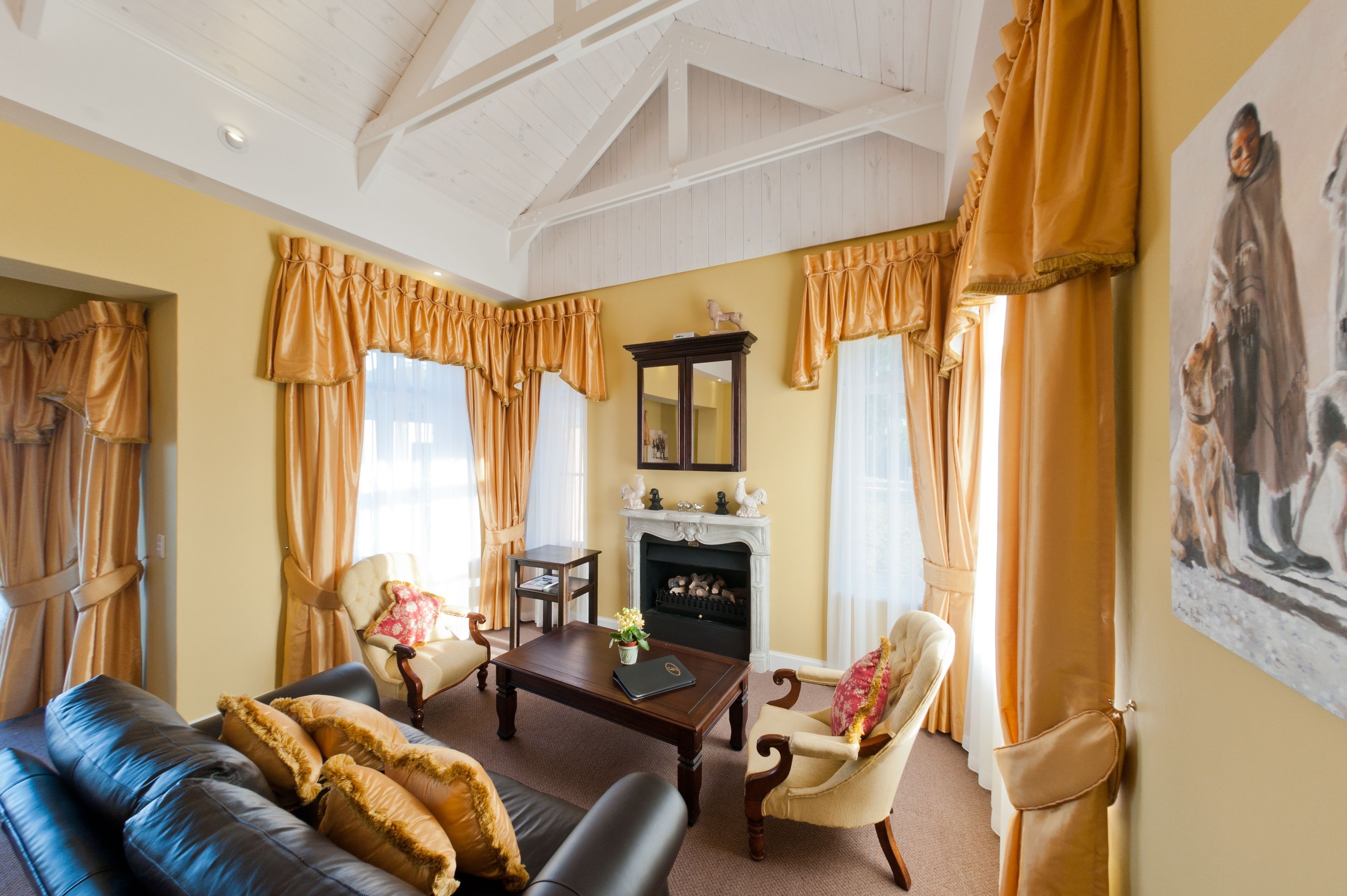 A traditional living room with a fireplace, leather sofa, and classic decor.