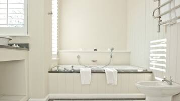 A modern bathroom with a bathtub, a sink, and a window.