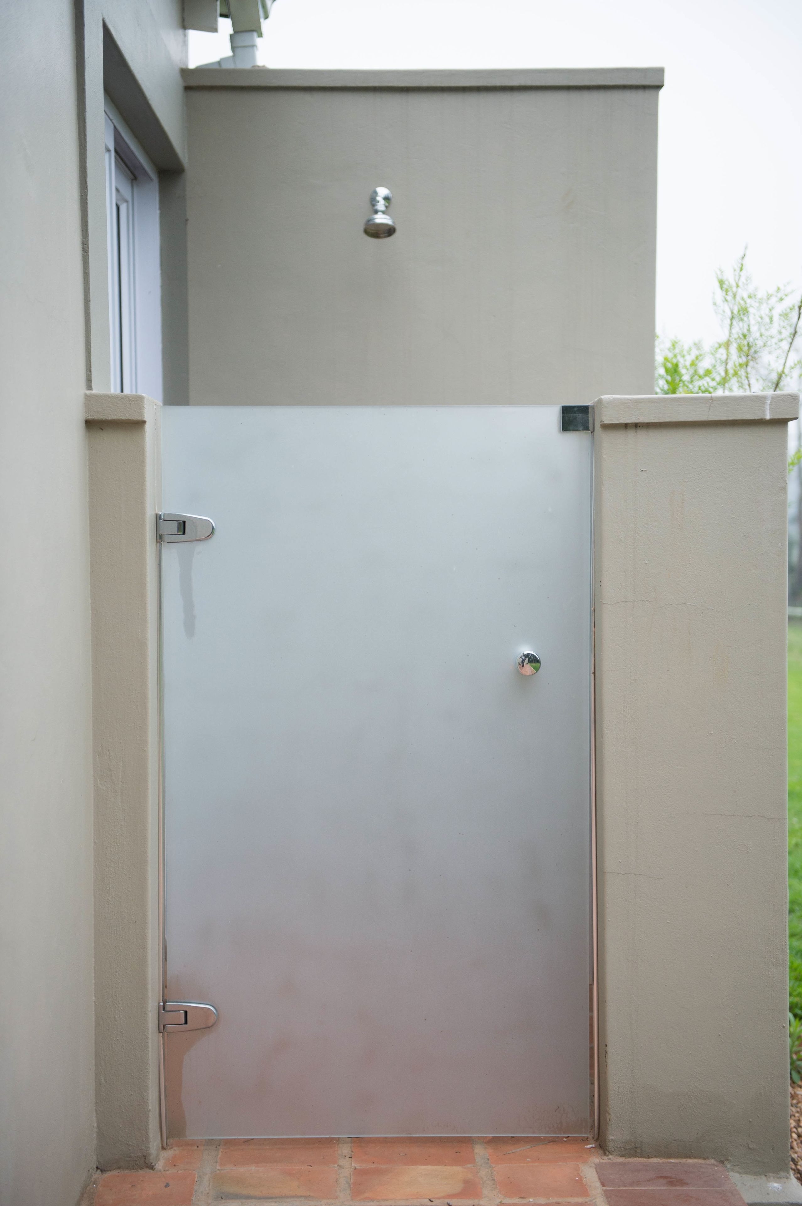A closed metal gate with a handle and a lock, set in a beige wall with a small window above it.