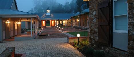 A courtyard with a central pathway leading to a building with a tower-like structure.