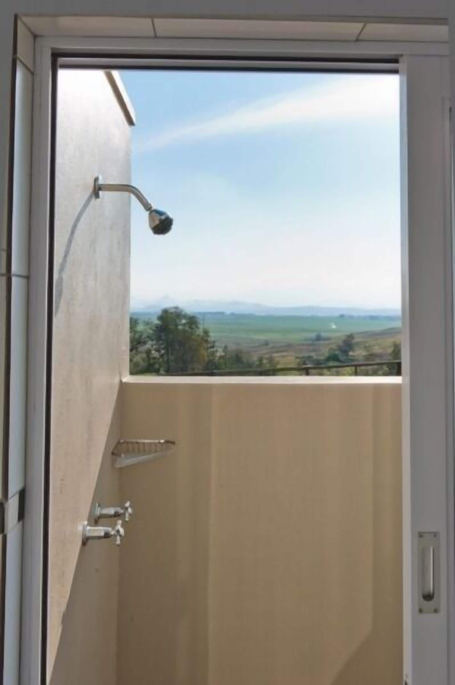 Un baño con ducha, vistas al campo y una puerta con manija.
