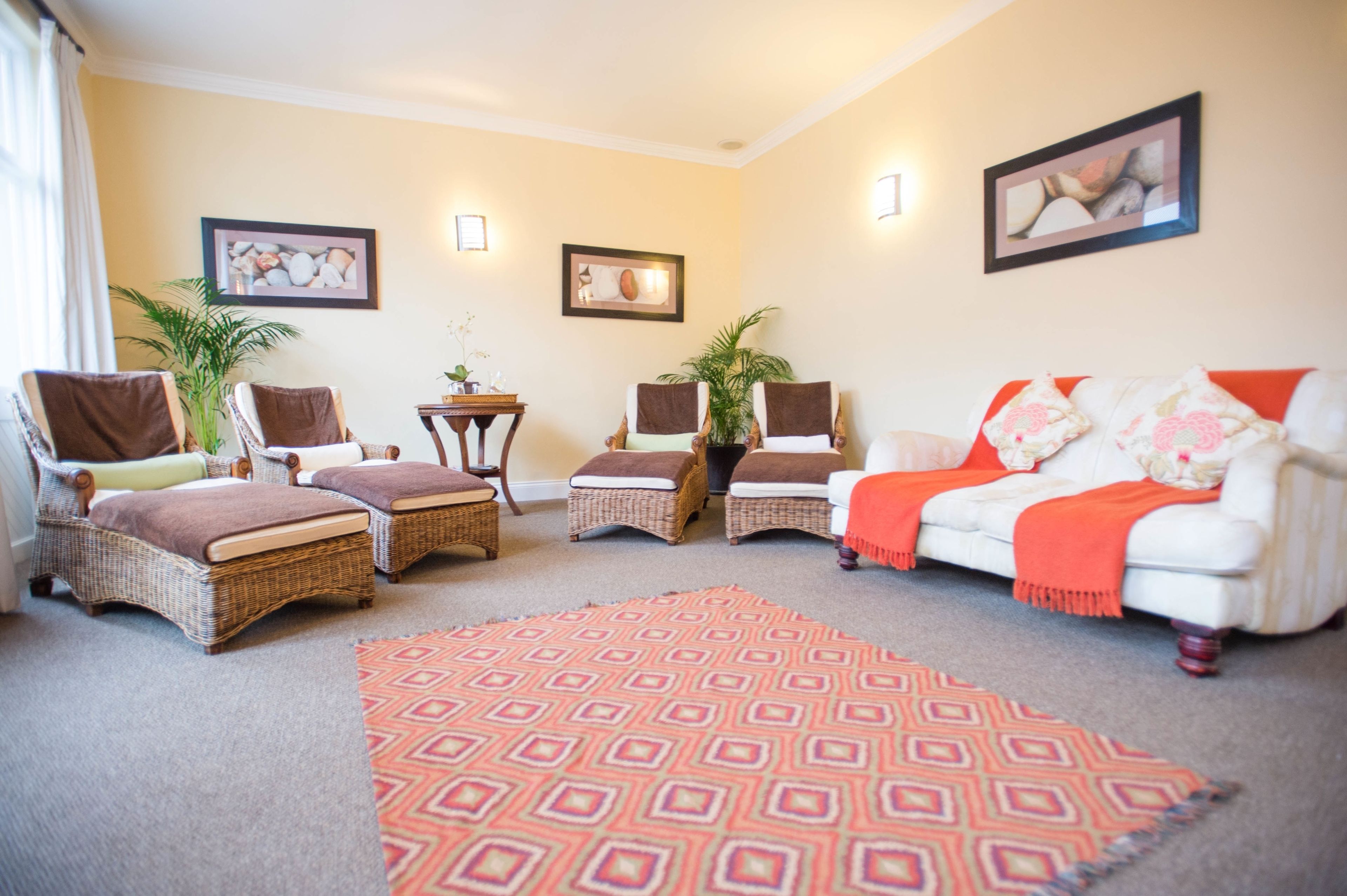 A living room with wicker furniture, a white sofa, and a patterned rug.