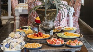 Un espace repas proposant une variété de plats, une grande plante décorative et un miroir orné d’un motif de feuilles.