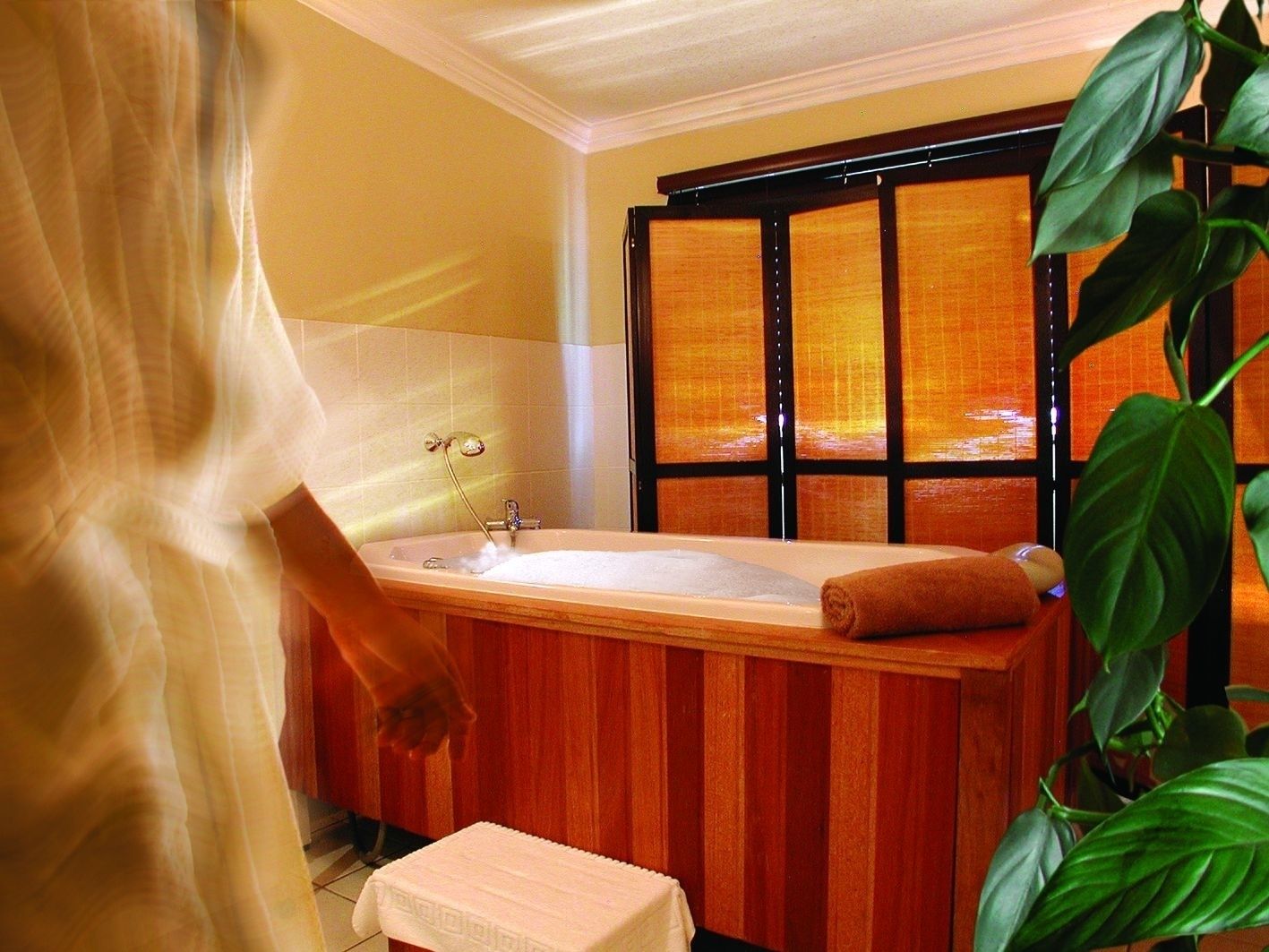 A bathroom with a wooden vanity, a bathtub, and a window with blinds.