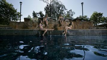 A swimming pool with stone walls and a gazebo in the background.