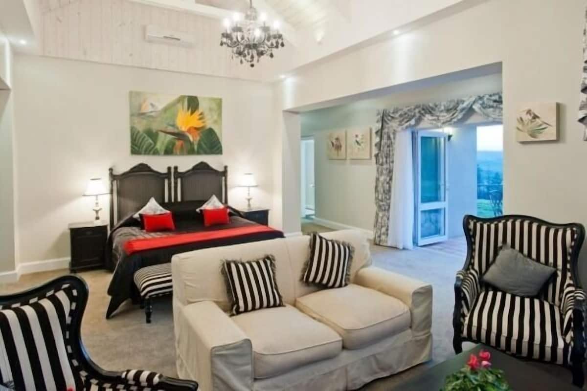 A bedroom with a bed, bedside tables, a sofa, and a chair.