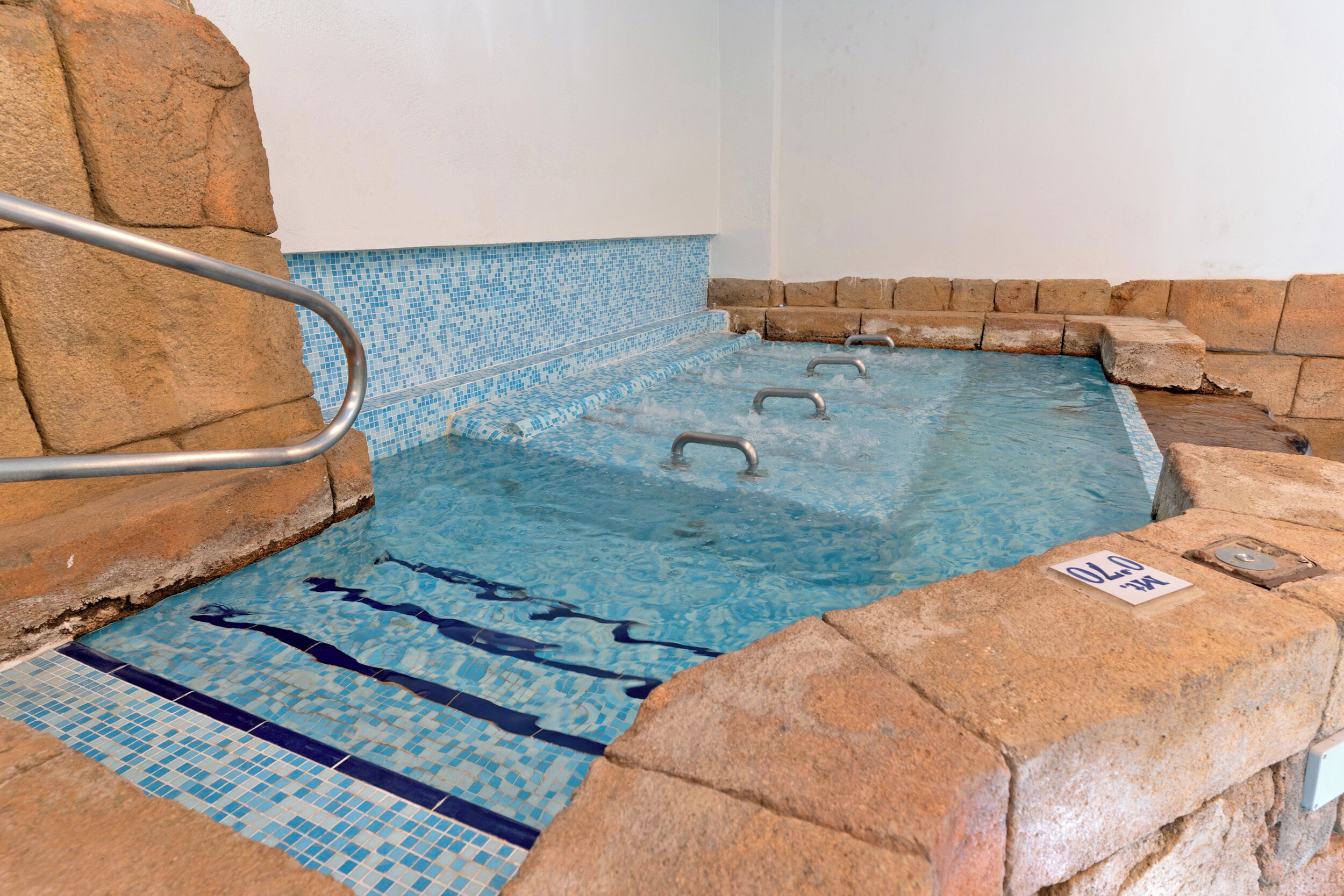 Un jacuzzi con piso de azulejos y barandas de metal.