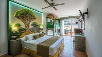 Une chambre dotée d’un grand lit, d’une fresque murale représentant un arbre verdoyant, d’une cheminée en pierre et d’un balcon avec des sièges d’extérieur.