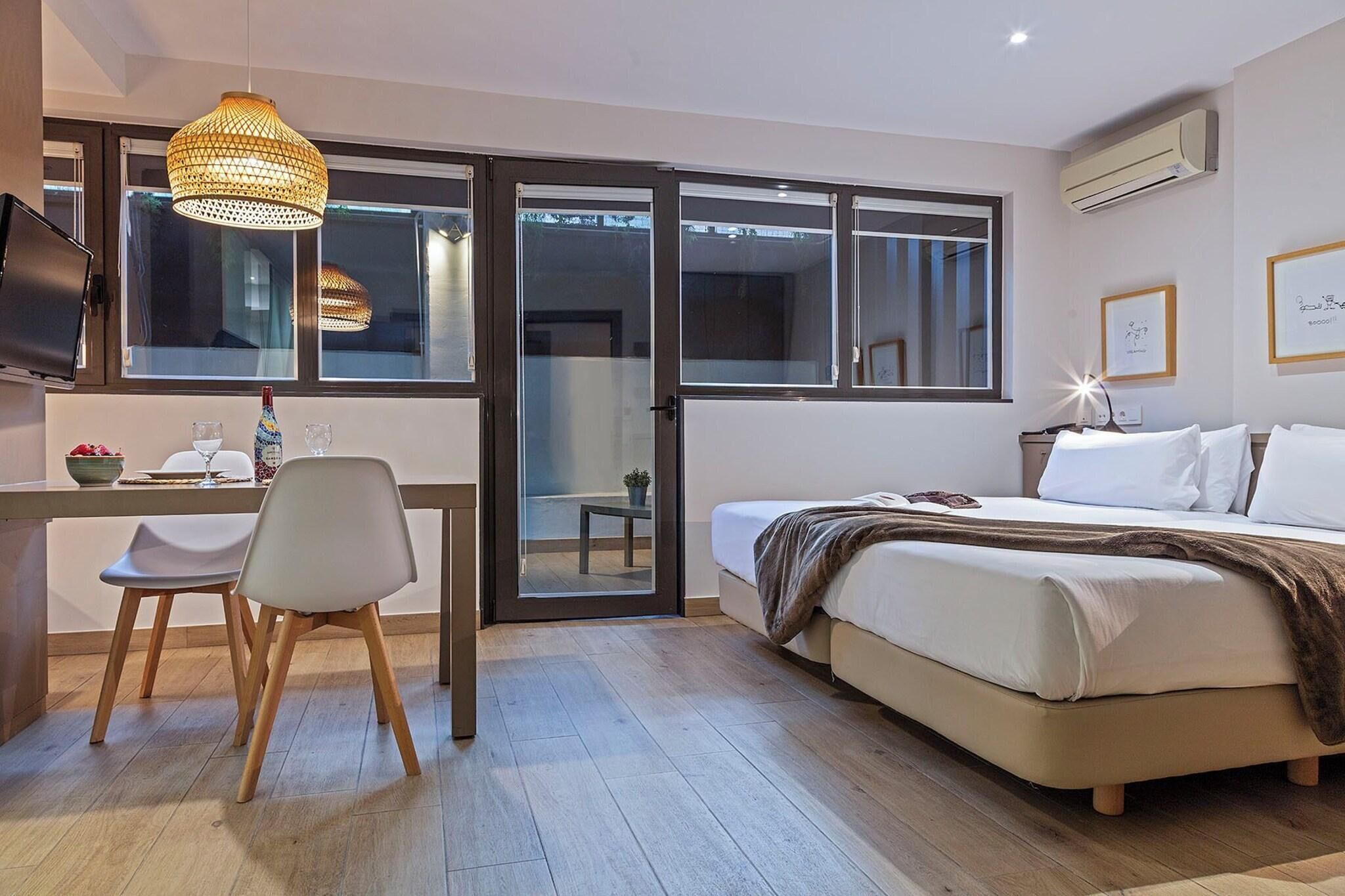 A modern bedroom with a bed, a desk, a chair, a TV, and a large window.