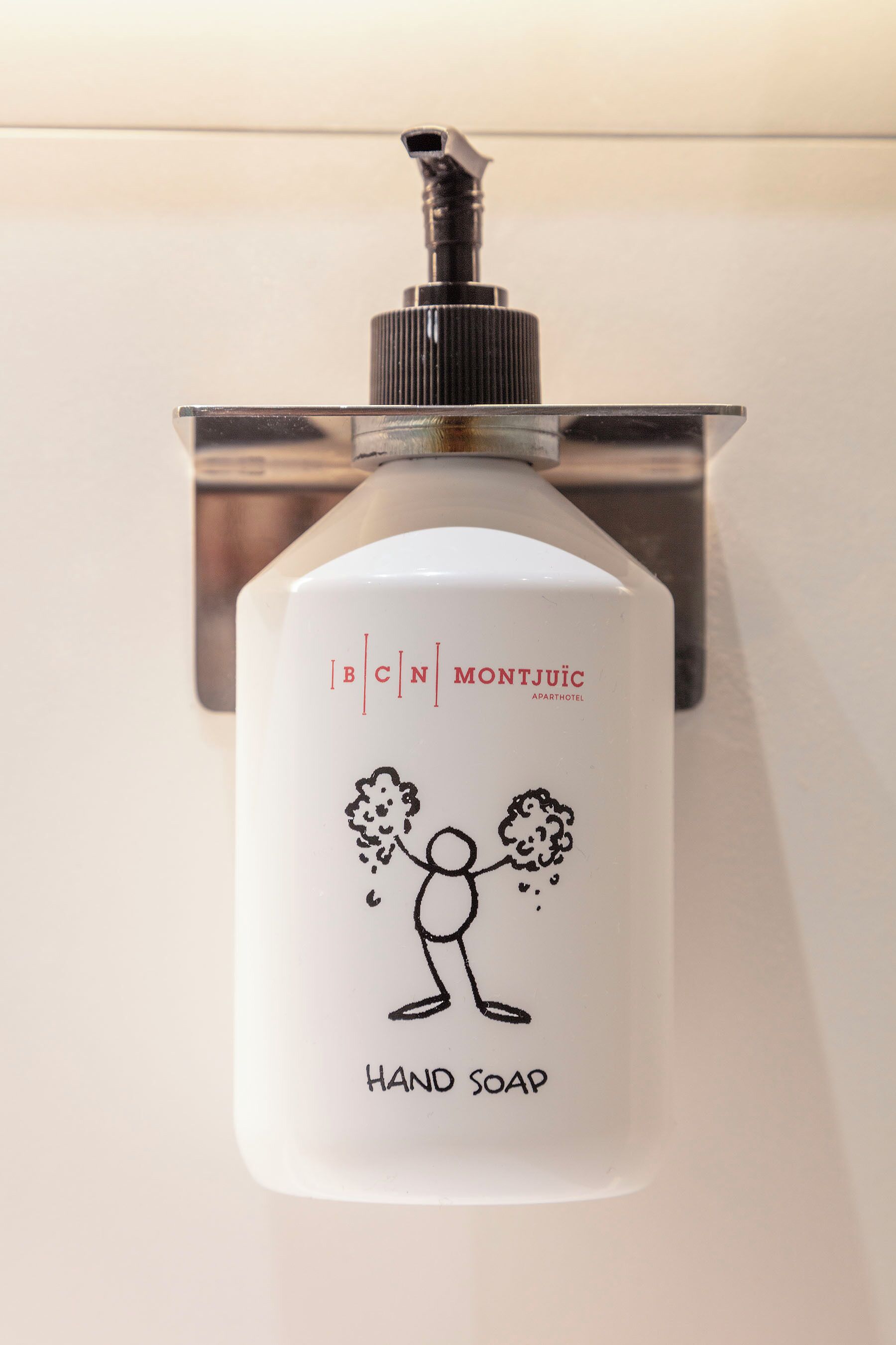 A hand soap dispenser with a cartoon character on it, mounted on a metallic wall.