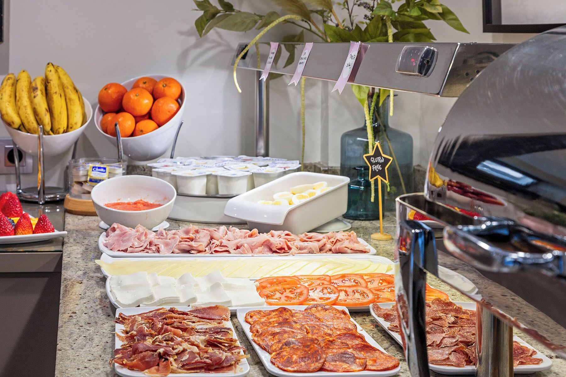 Un bufé con diversas opciones de comida, incluyendo frutas, carnes y quesos.