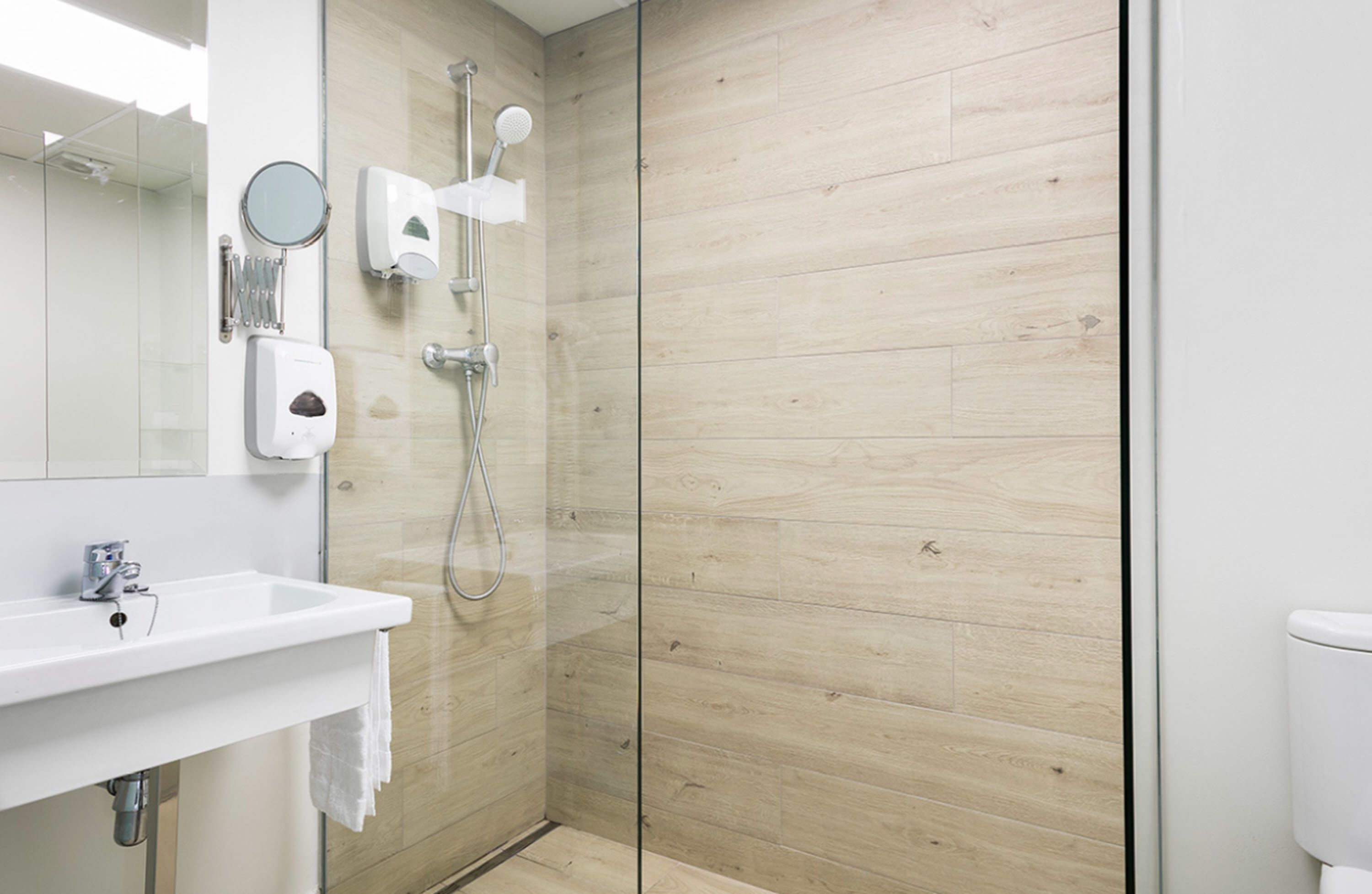 Een moderne badkamer met een douchecabine van glas, een wit wastafelmeubel en een toilet.