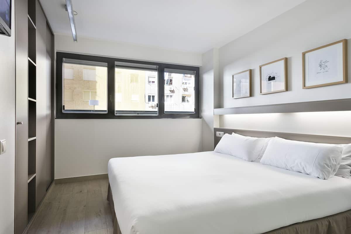 A bedroom with a bed, a window, and three framed pictures on the wall.