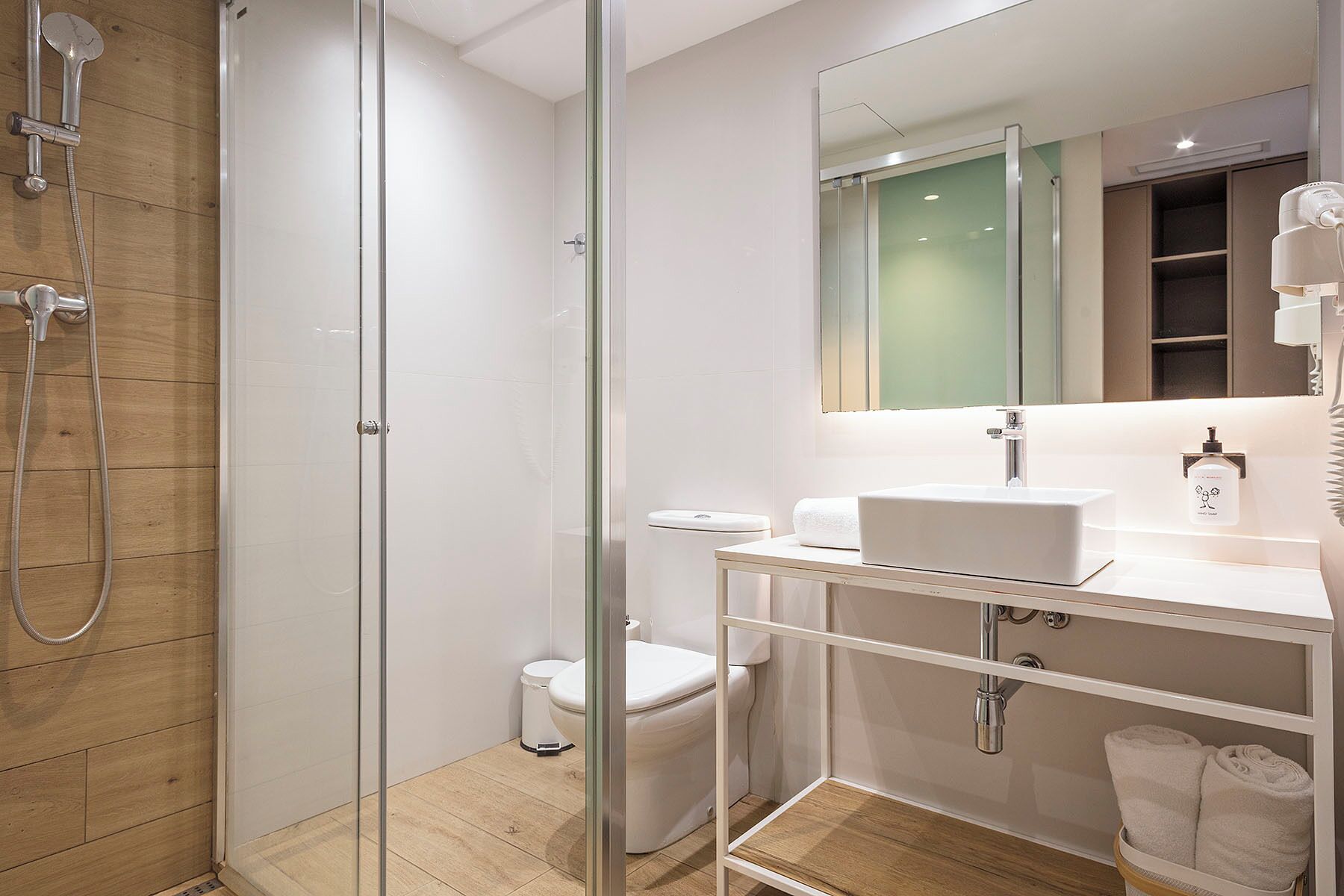 Un baño moderno con cabina de ducha de vidrio, un lavabo blanco y un espejo sobre él.