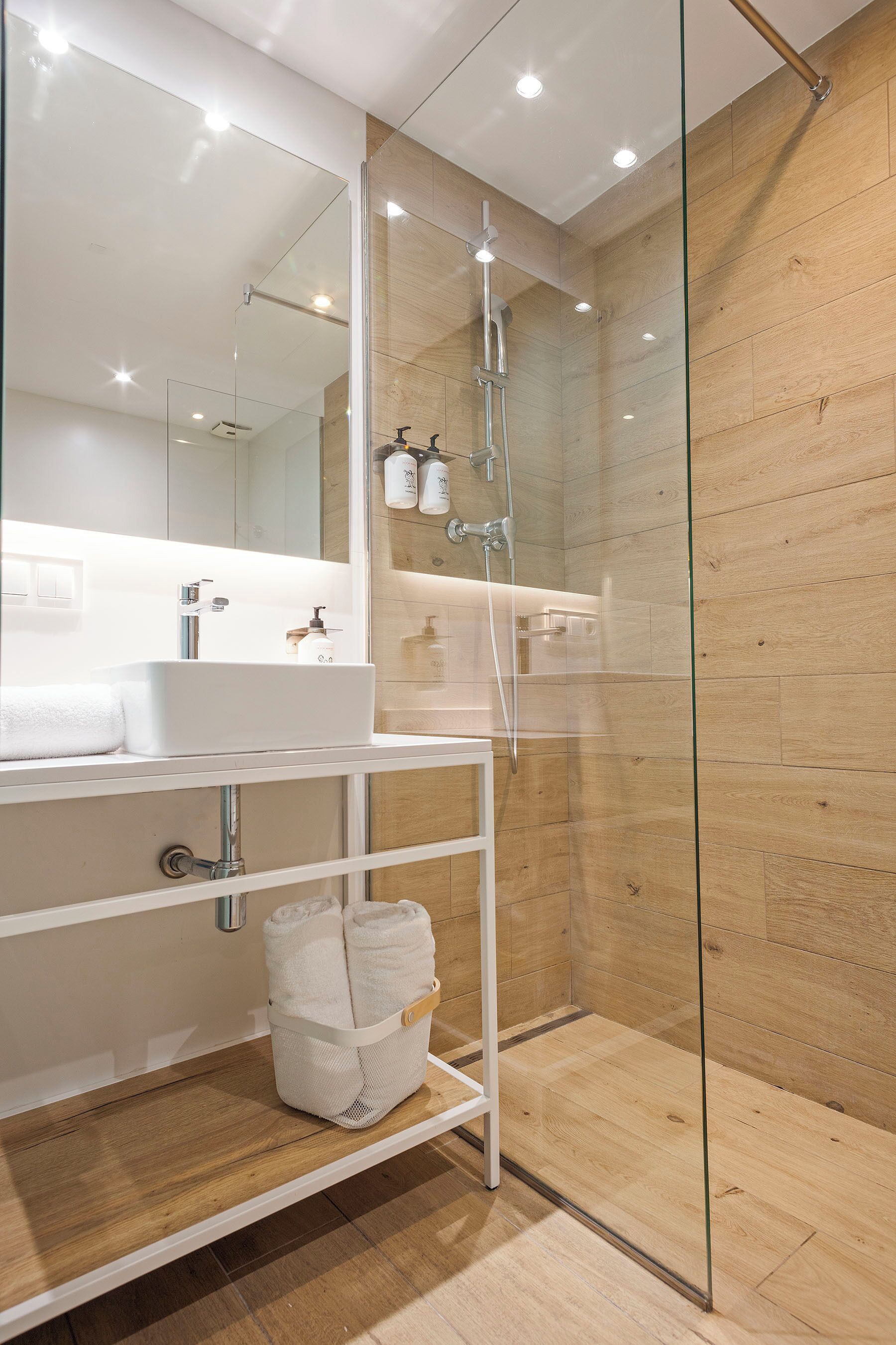 A modern bathroom with a glass shower enclosure, a white sink, and a mirror above it.