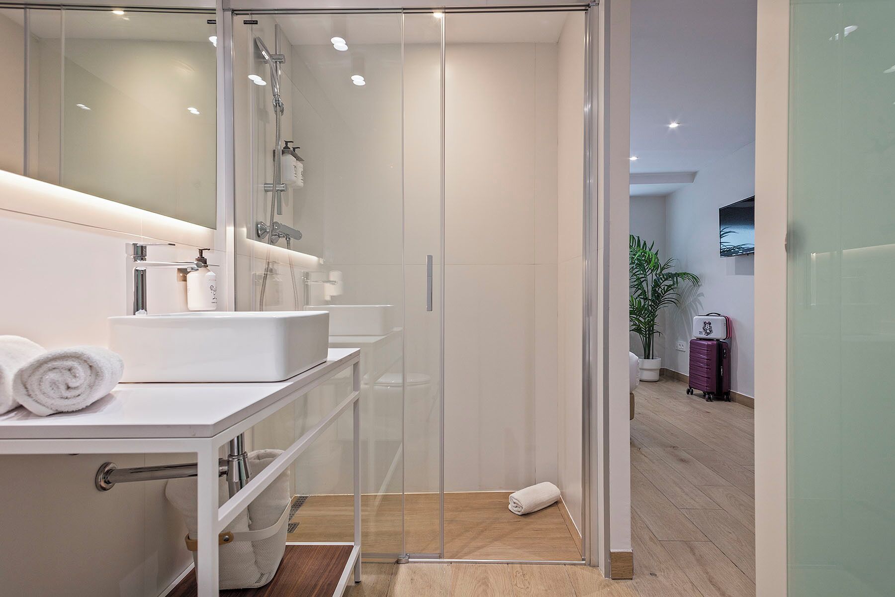 Un baño moderno con ducha de vidrio, un lavamanos blanco y un espejo.