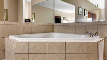 A large, rectangular bathtub with a modern faucet, set against beige tiled walls.