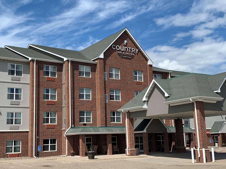 Ein Country Inn & Suites Gebäude mit Ziegelverkleidung, zahlreichen Fenstern und einem grünen Dach.