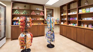 Interior de una tienda con estantes llenos de aperitivos, juguetes y otros productos.