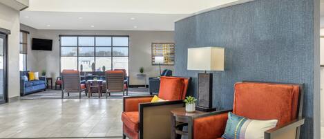 A spacious lobby with a seating area, a television mounted on the wall, and a large window providing a view of the outside.