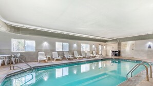 An indoor swimming pool with clear water, surrounded by white lounge chairs and a tiled floor. - Comfort Suites Nacogdoches (Nacogdoches)