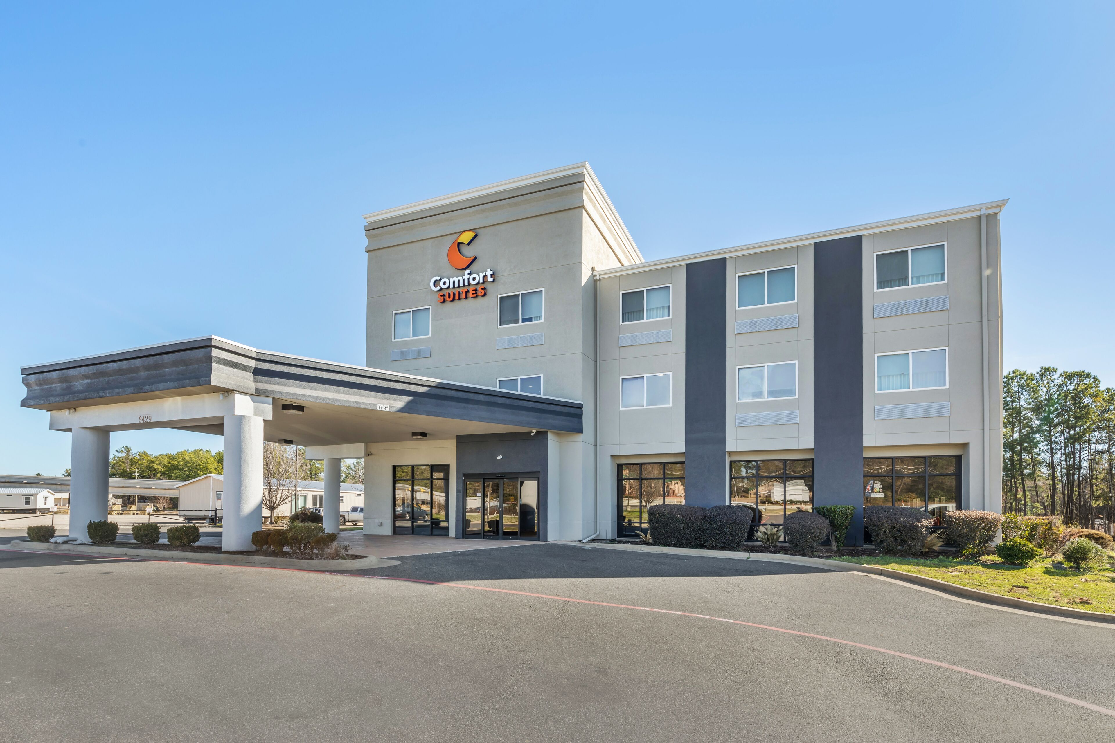 Et Comfort Suites hotel med et moderne design, der inkluderer en overdækket indgang og flere etager.