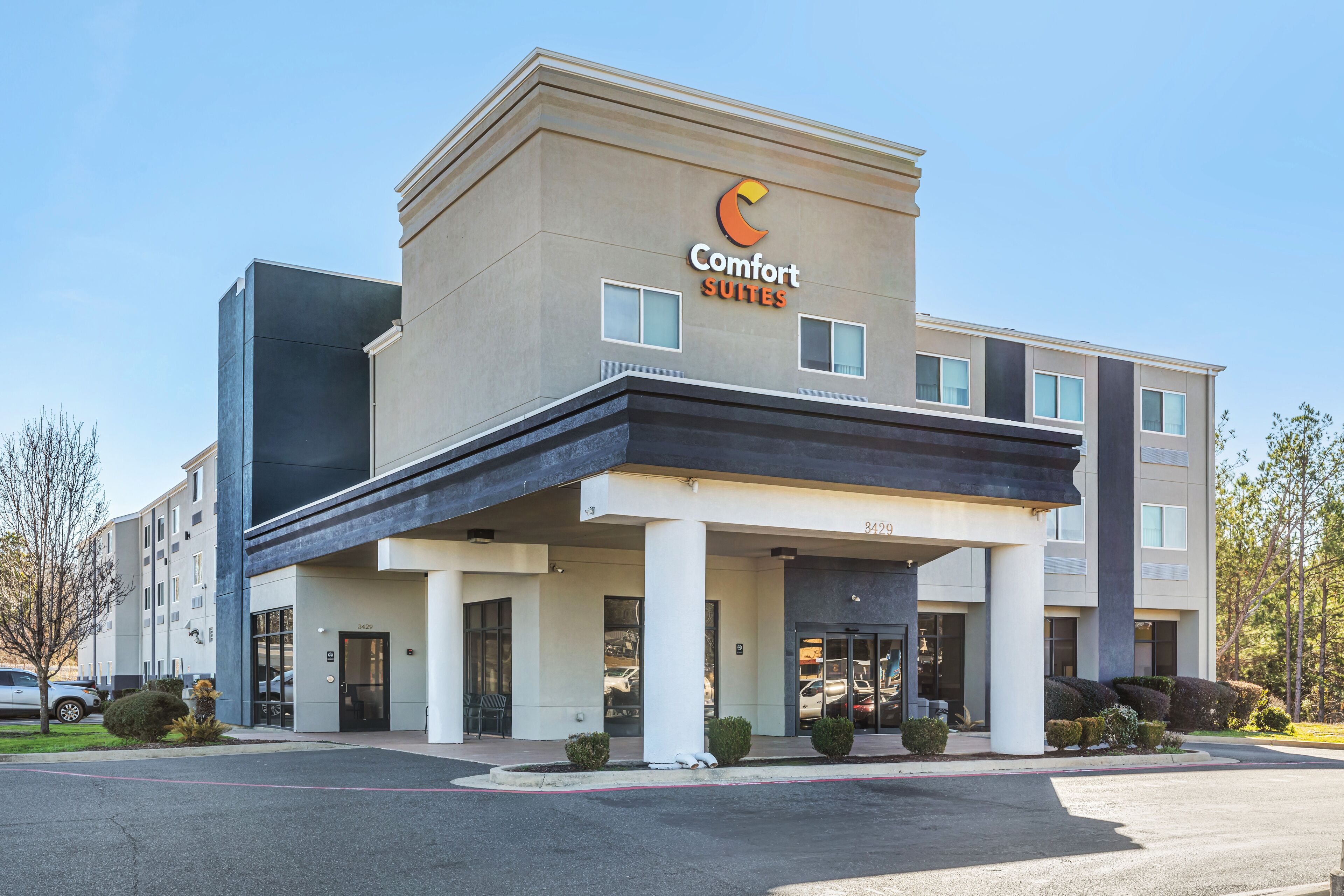 A Comfort Suites hotel with a modern facade, a covered entrance, and a parking lot.