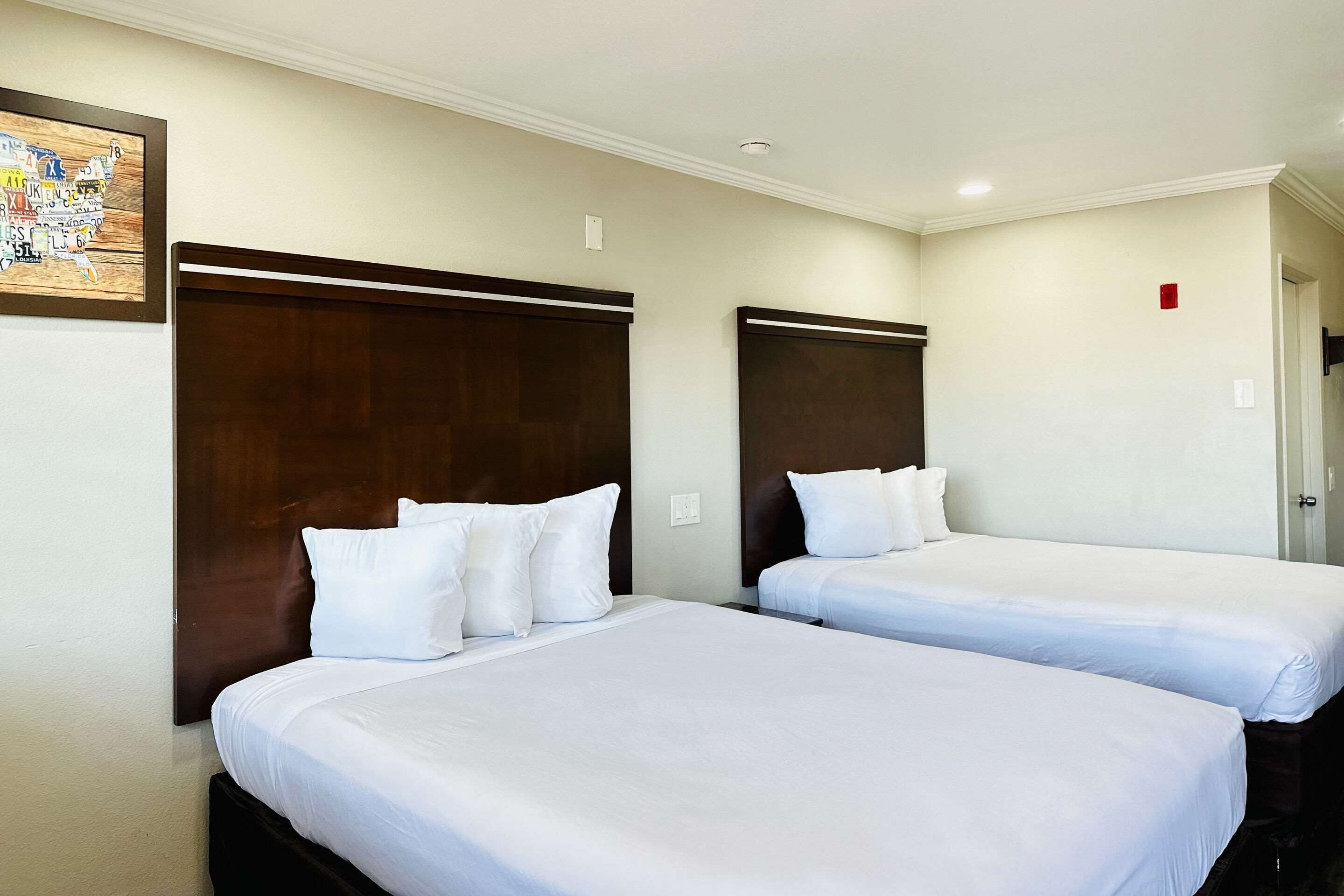 A hotel room with two single beds, each with white bedding and a wooden headboard.