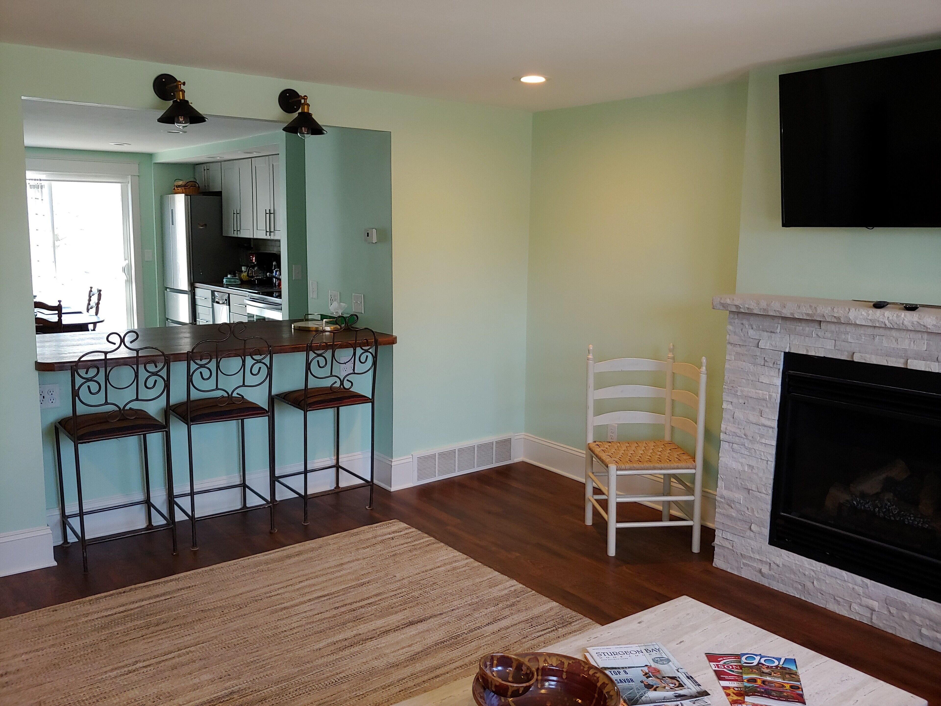 A living room with a fireplace, a kitchen area, and a dining space.