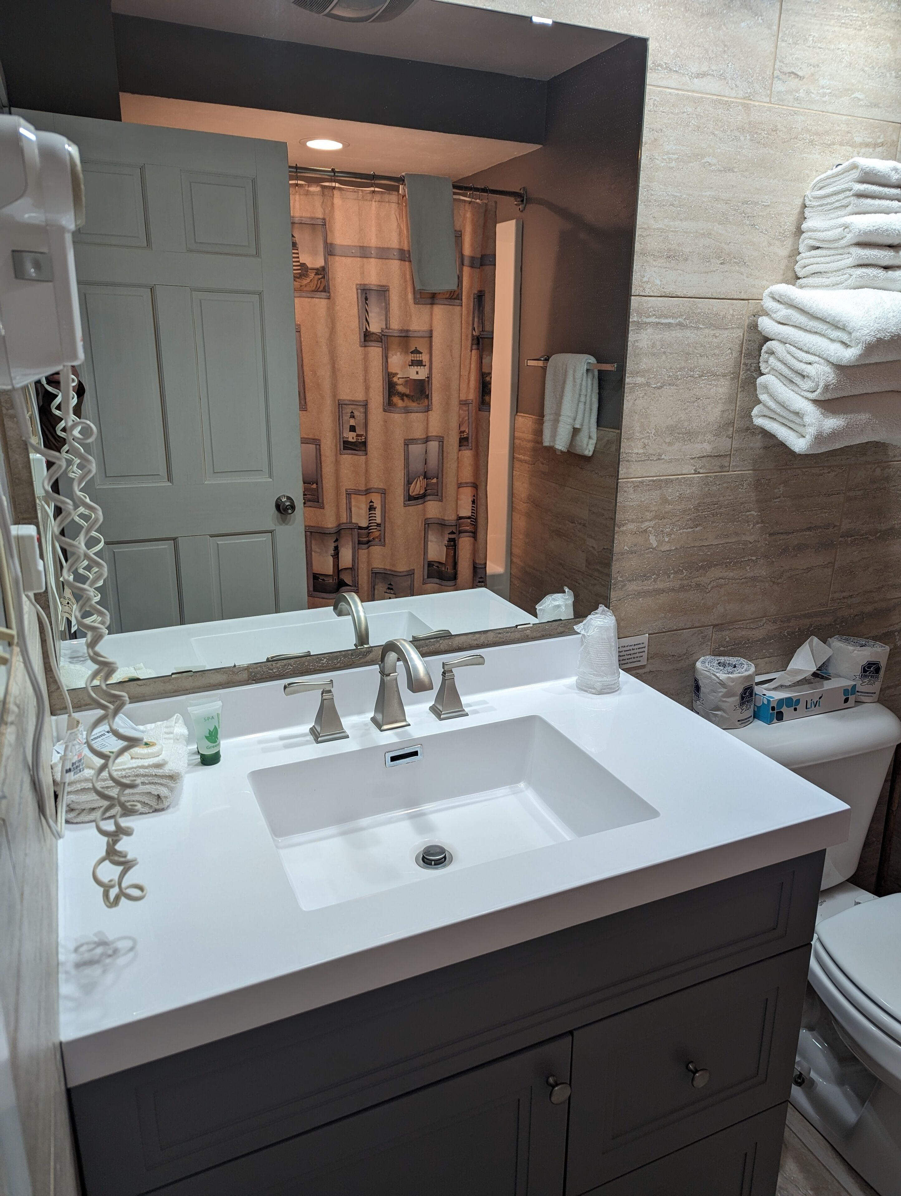 A bathroom with a white sink, two faucets, a mirror, and a towel rack with folded towels.
