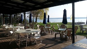 An outdoor seating area with tables and chairs, umbrellas, and a view of a body of water. - Beach Harbor Resort (Sturgeon Bay)