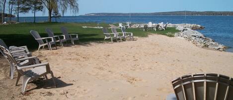 Une plage bordée de rangées de chaises Adirondack et d’une zone herbeuse.