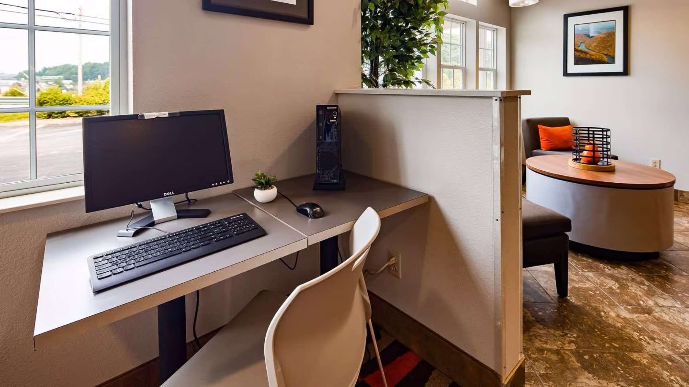 Un bureau moderne, de type « open space », équipé d’un écran Dell, d’un clavier et d’une petite plante en pot.