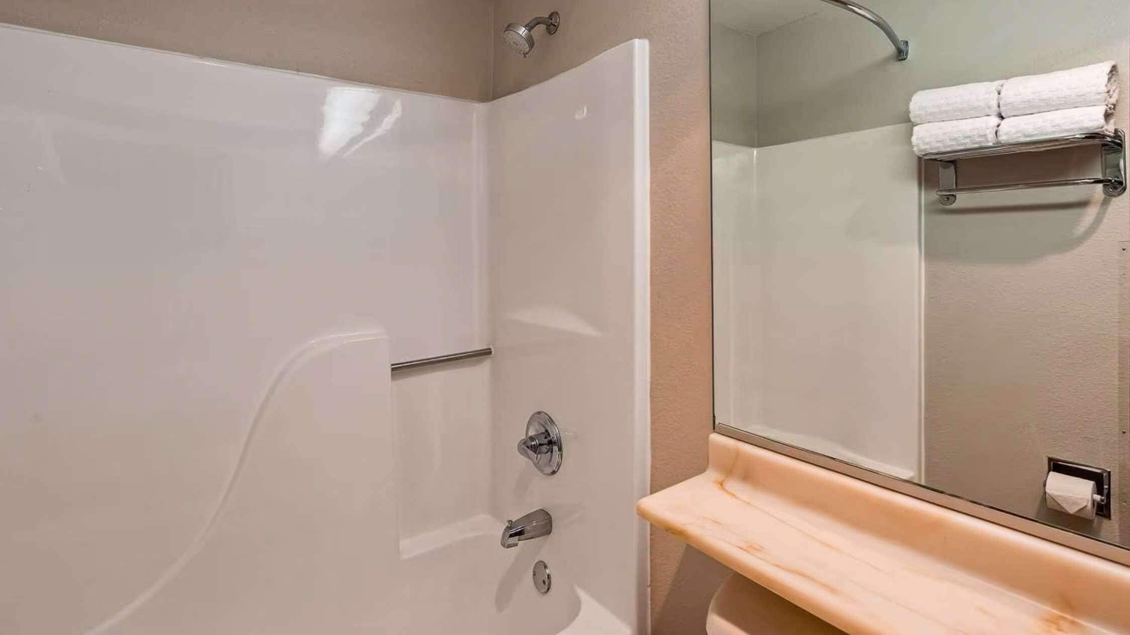 A modern bathroom with a walk-in shower, a glass-enclosed toilet, and a wooden vanity with a towel rack.