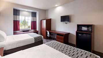 A hotel room with two beds, a desk, a chair, a TV, and a minibar.