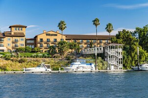 Un hotel frente al agua con varios balcones, un muelle con barcos y un edificio blanco con la señalización 'WESTIN'.
