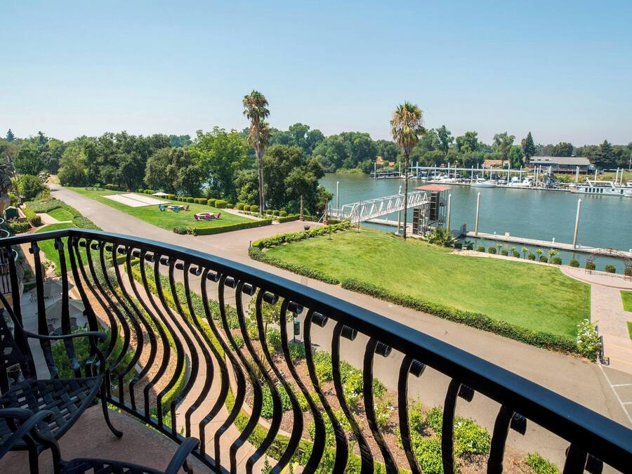 Ein Balkon mit Blick auf einen Hafen, eine Brücke und einen gepflegten Rasen.