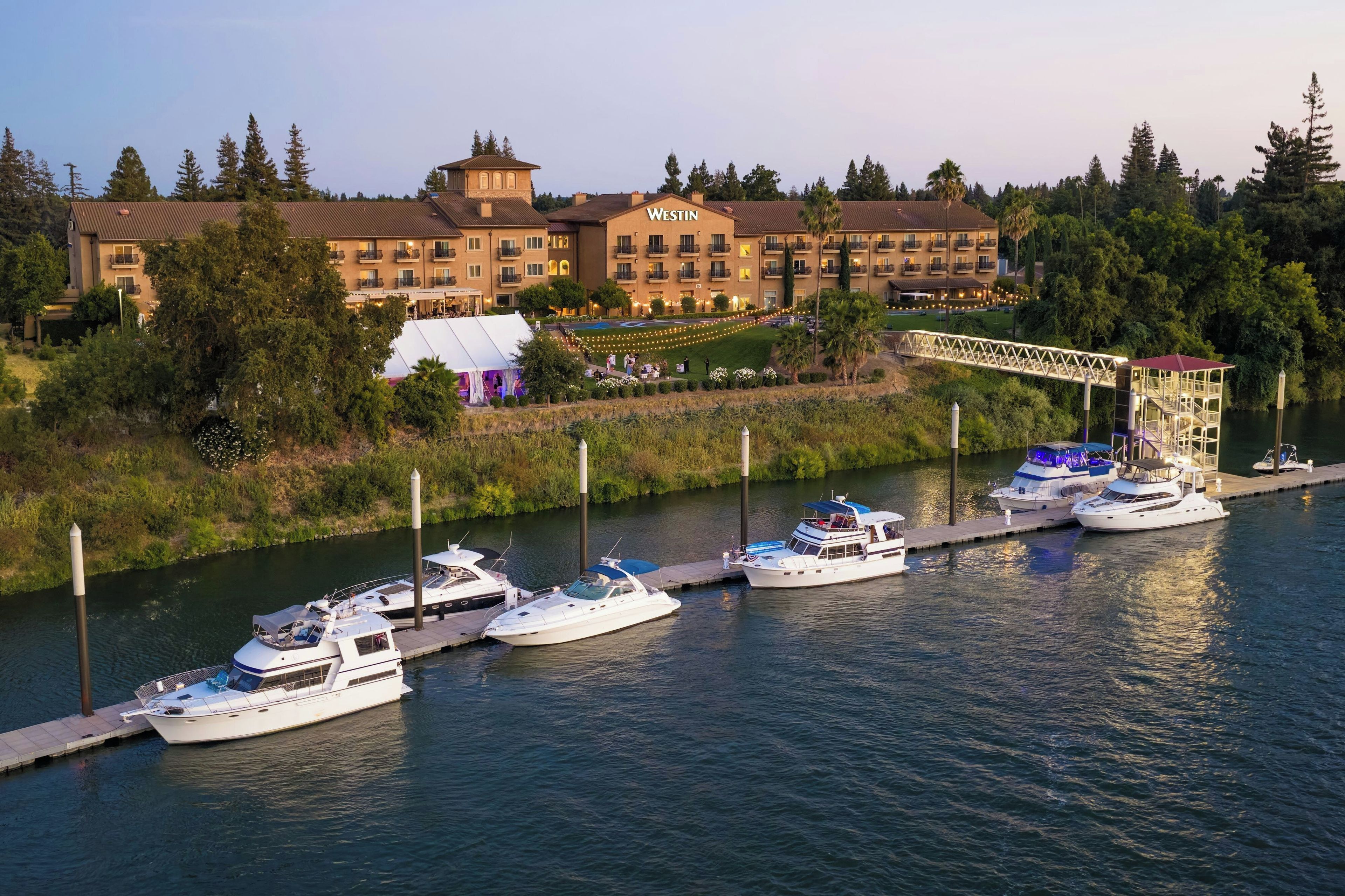 A waterfront property with multiple boats docked, a bridge, and a large building with balconies.
