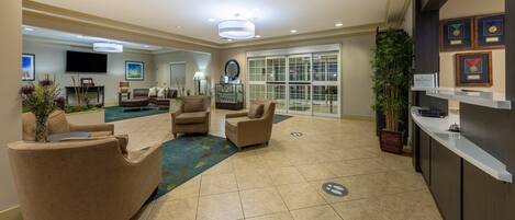 A spacious lobby with a pool, comfortable seating, and a reception desk.